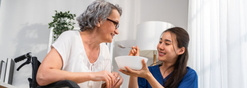 caretaker feeding senior woman patient