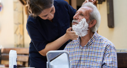 caregiver shave the beard of senior man