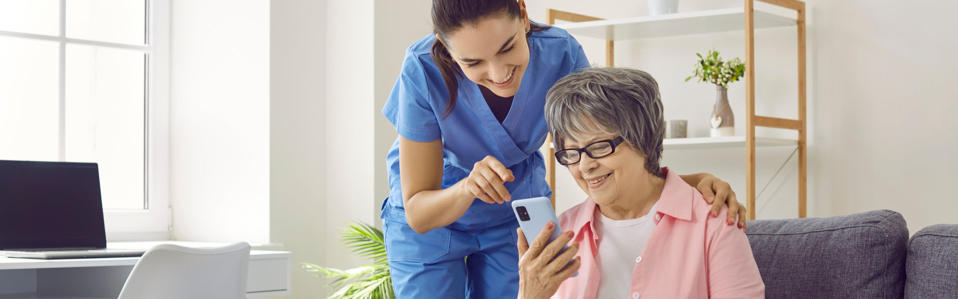 senior woman using mobile phone with caretaker